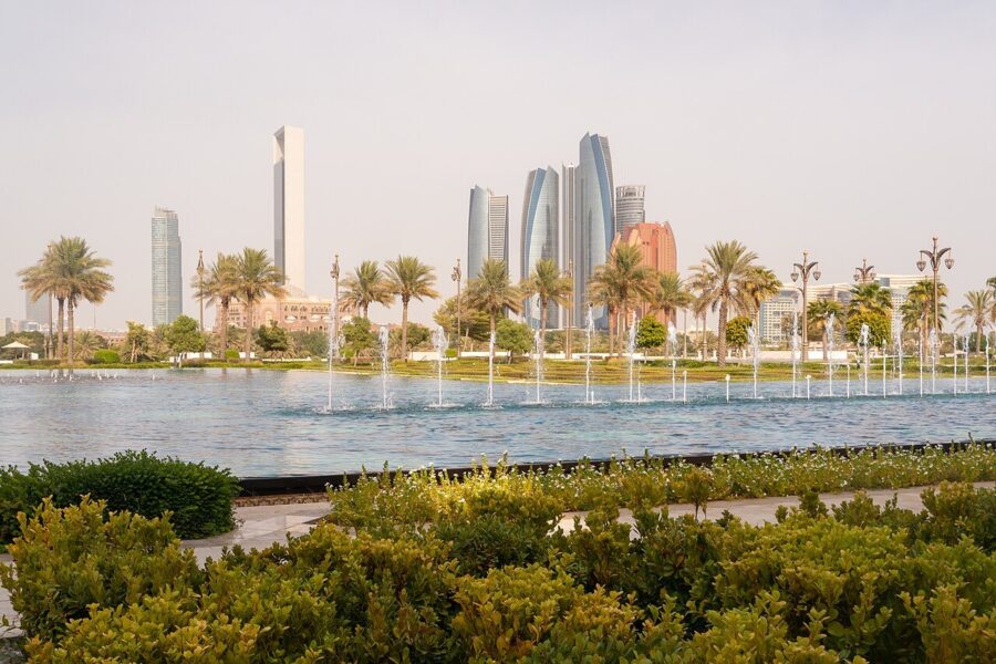 Fountains and palm trees in the gardens of Qasr Al Watan with Abu Dhabi's towers on the skyline behind