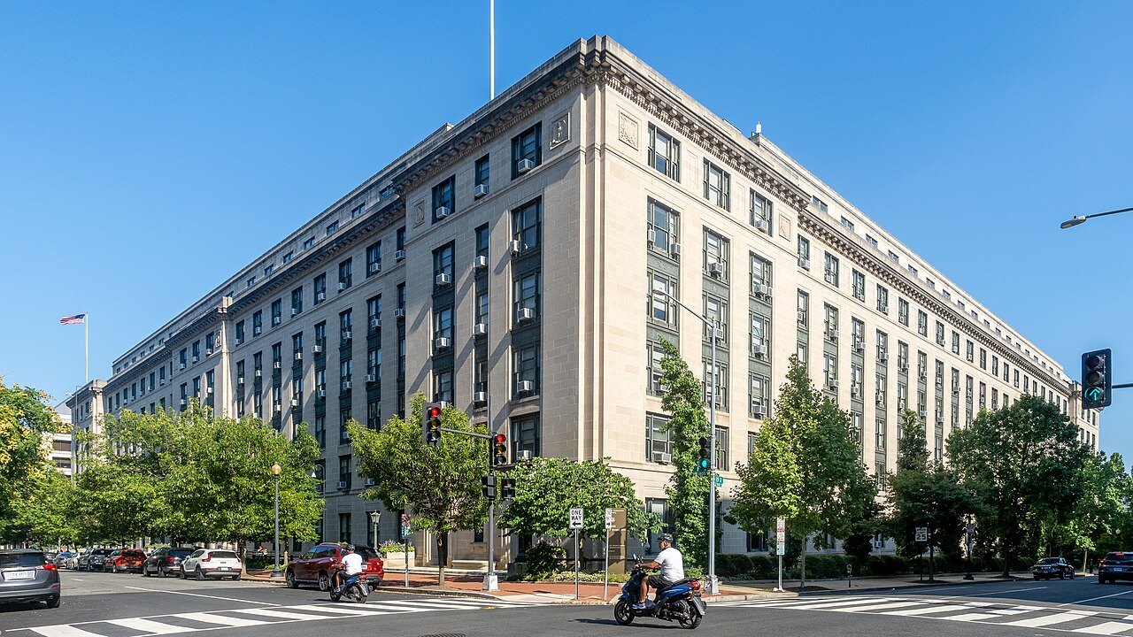 The pale stone General Services Administration headquarters building in Washington, DC, seen from a street corner under a clear blue sky