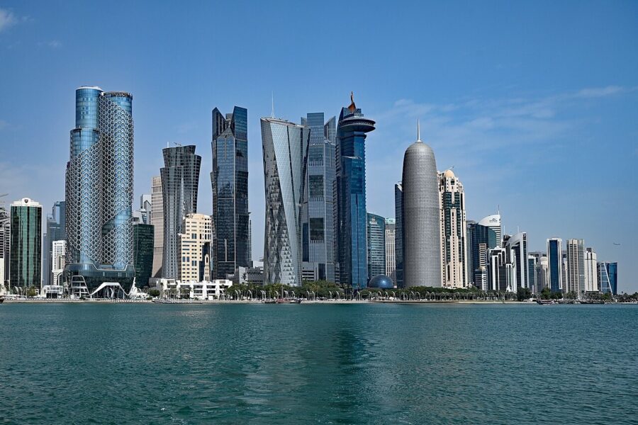 High-rise office towers along the West Bay waterfront in Doha, Qatar, seen across the bay in daylight.