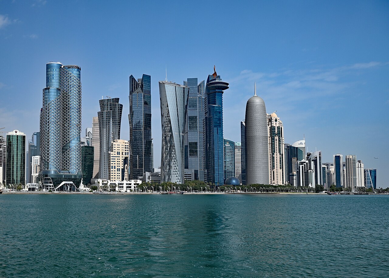 High-rise office towers along the West Bay waterfront in Doha, Qatar, seen across the bay in daylight.